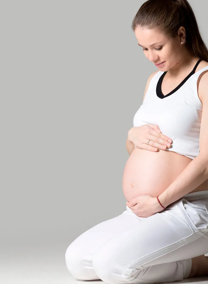 Gestante segurando a barriga durante acompanhamento obstétrico